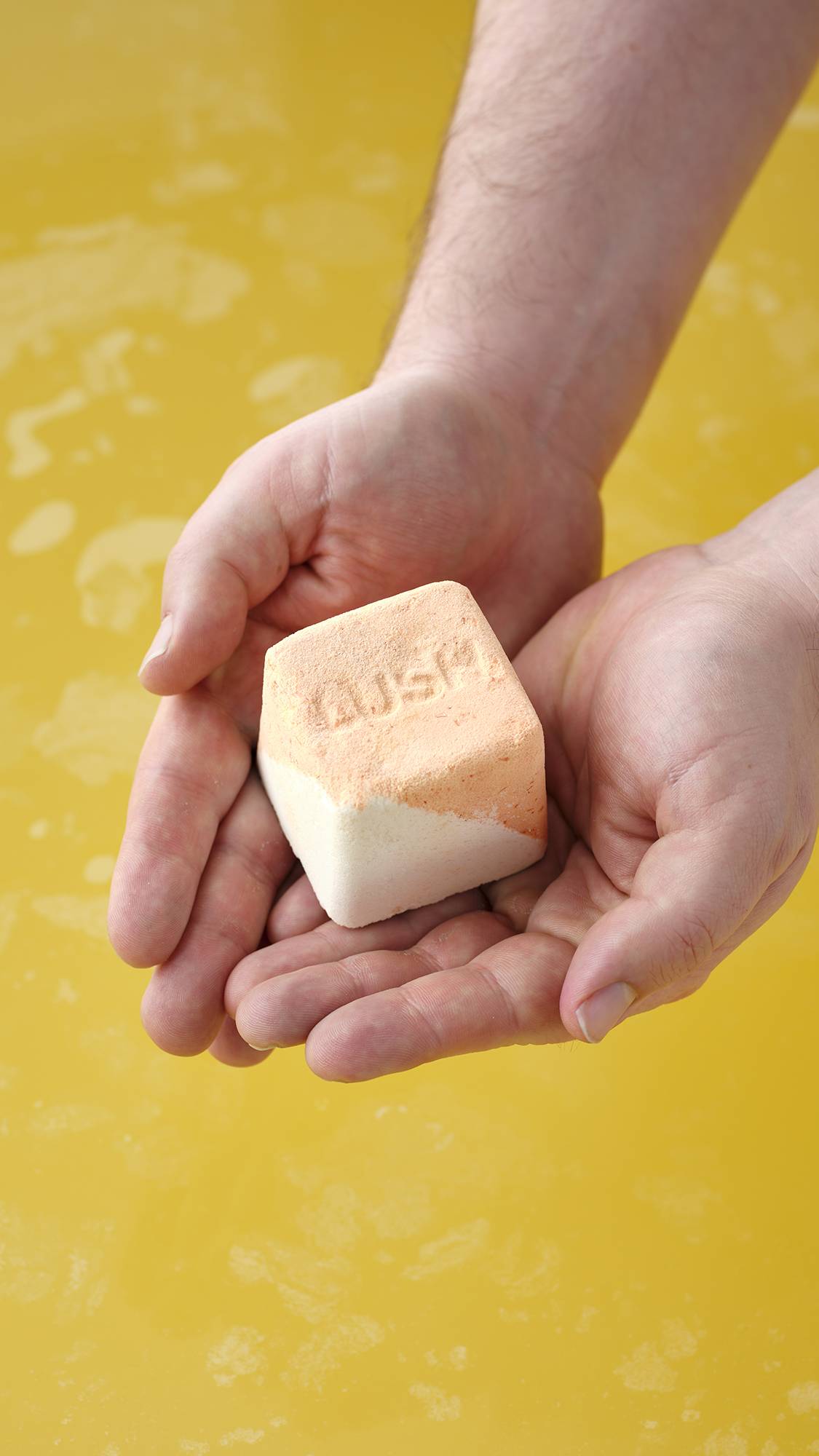 The Cold Water Soother bath bomb sits on a plain, light gray background. The spherical product is primarily a pale, icy blue with a marbled, textured surface featuring subtle white and yellow highlights.