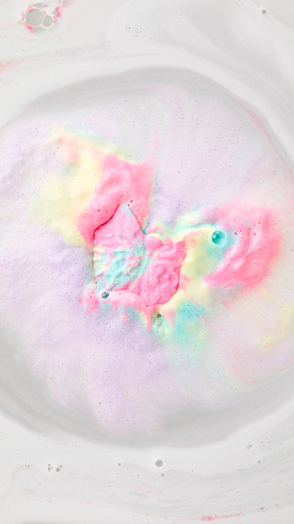 A top-down view of the Luna Butterfly bath bomb dissolving in milky white water. It creates a vibrant "bath art" explosion of neon pink, soft yellow, and bright turquoise foam that swirls outward in a cloud of colorful bubbles.