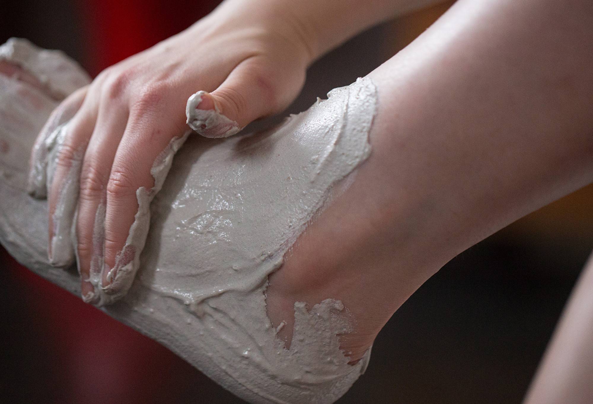 Volcano, a creamy grey coloured foot mask, is rubbed onto the top of a foot already coated in the mask from heel to toe.