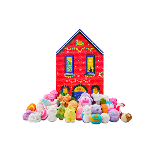 A red brick house-shaped gift box stands behind a large display of festive bath products, including a sleeping fox, a bear, a penguin, and a Christmas tree bath bomb, among many more themed products.