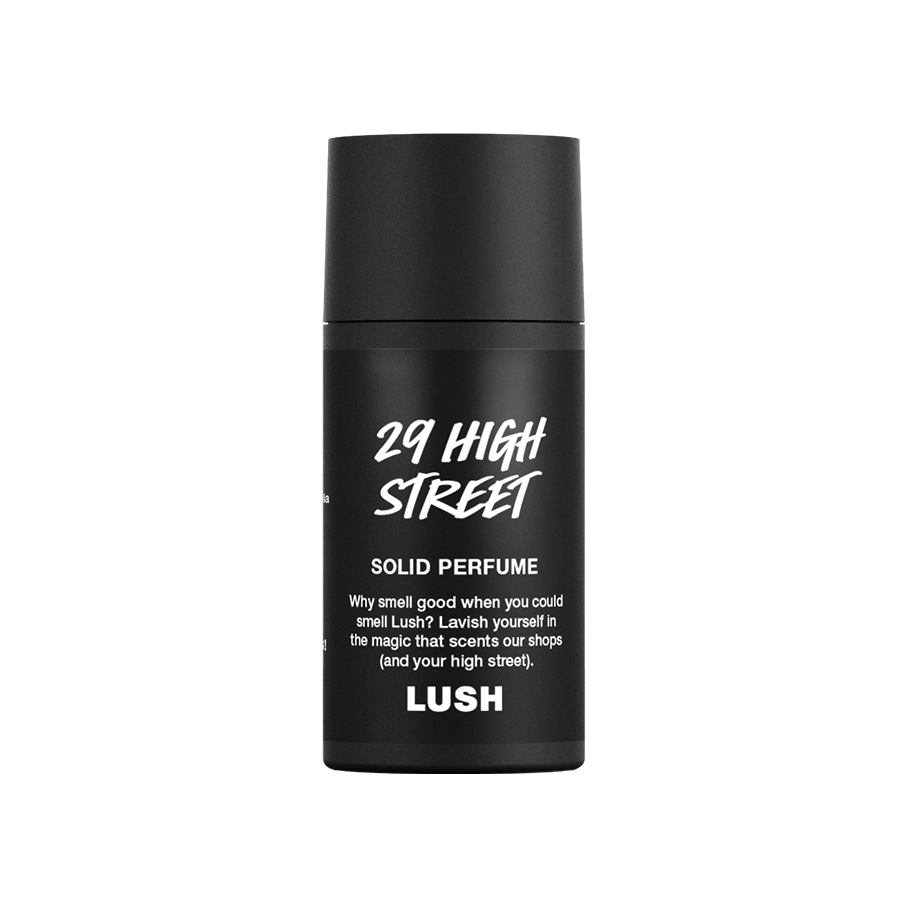 A small, cylindrical black, twist-up tube of Lush '29 High Street' solid perfume. The matte black packaging features white text including the product name, a brief description, and the Lush logo.
