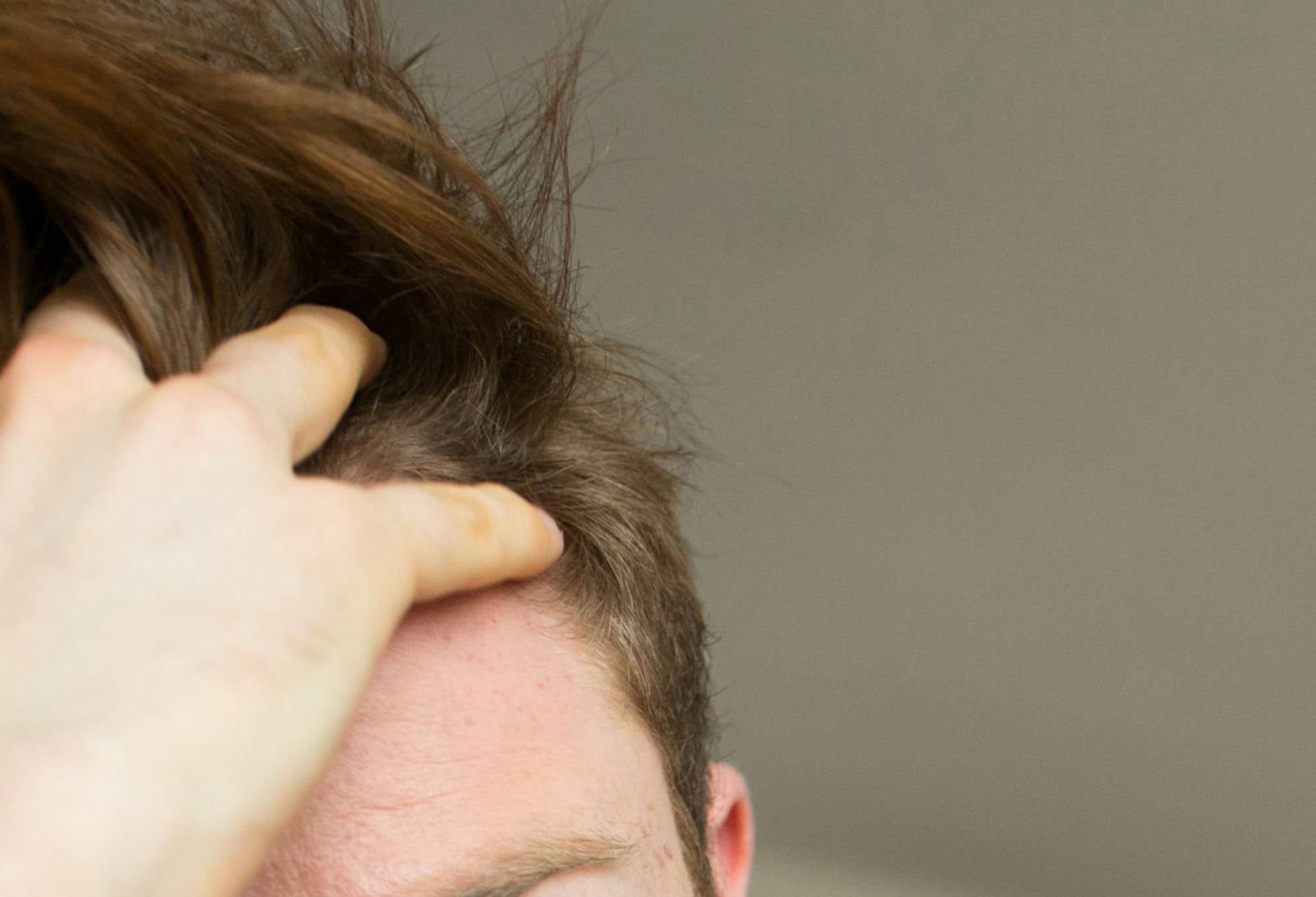 A person ruffles their hand through their hair, creating a volumised look.