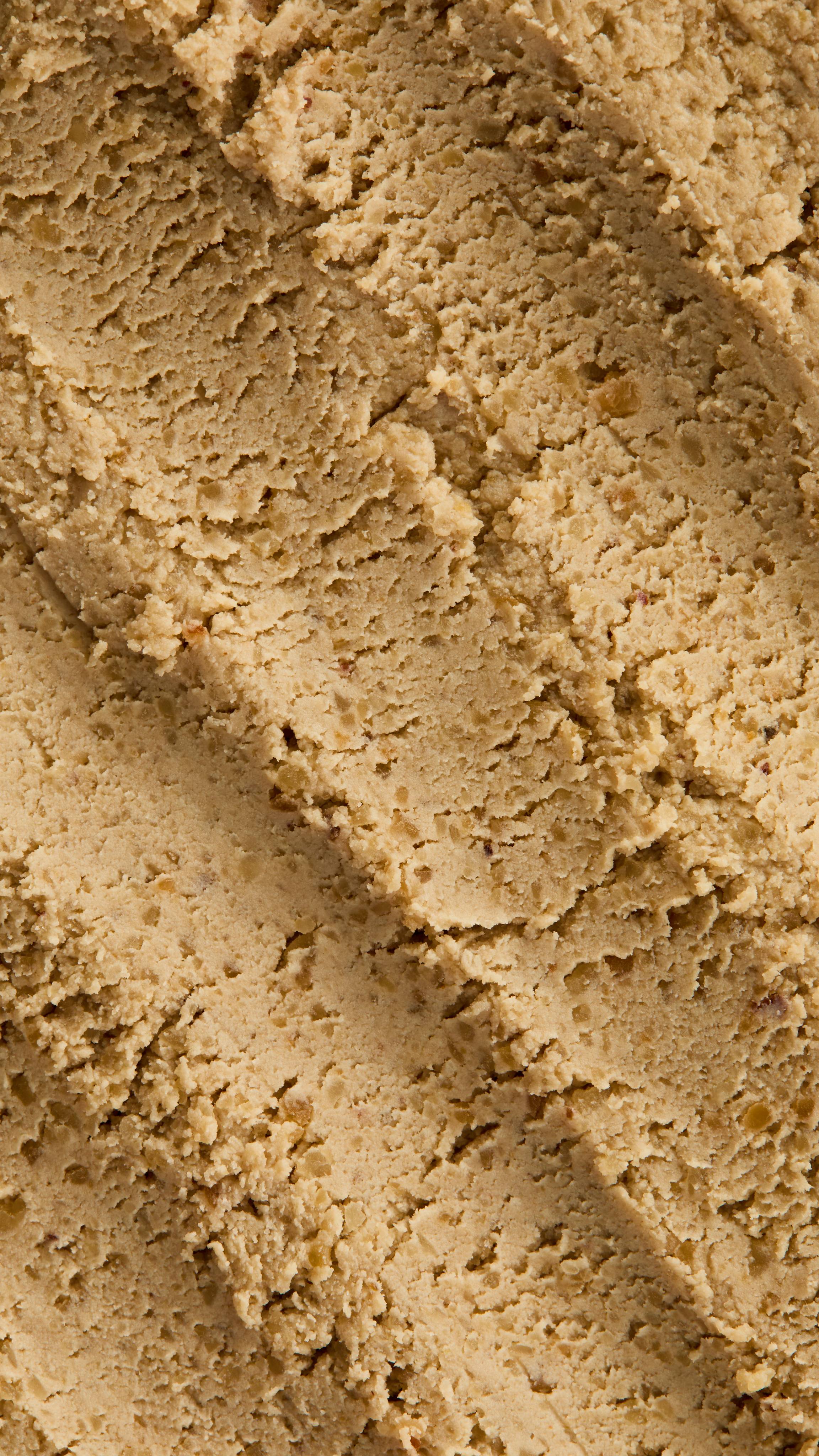 A super close-up image of the sand/ivory-coloured, textured Biomic facial cleanser, focusing on the consistency of grainy dough.