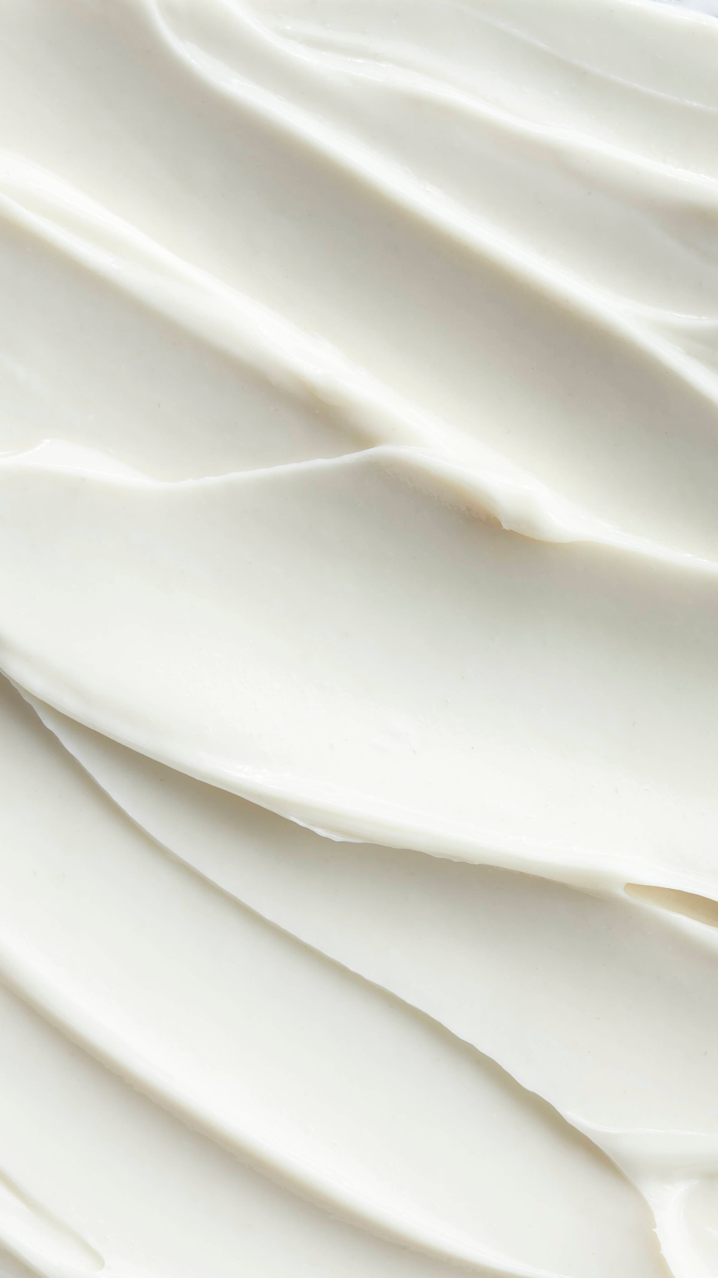 A detailed, close-up shot of Super Milk conditioner with soft, swooping peaks and valleys. The texture appears rich and luxurious, inviting the viewer to touch it.