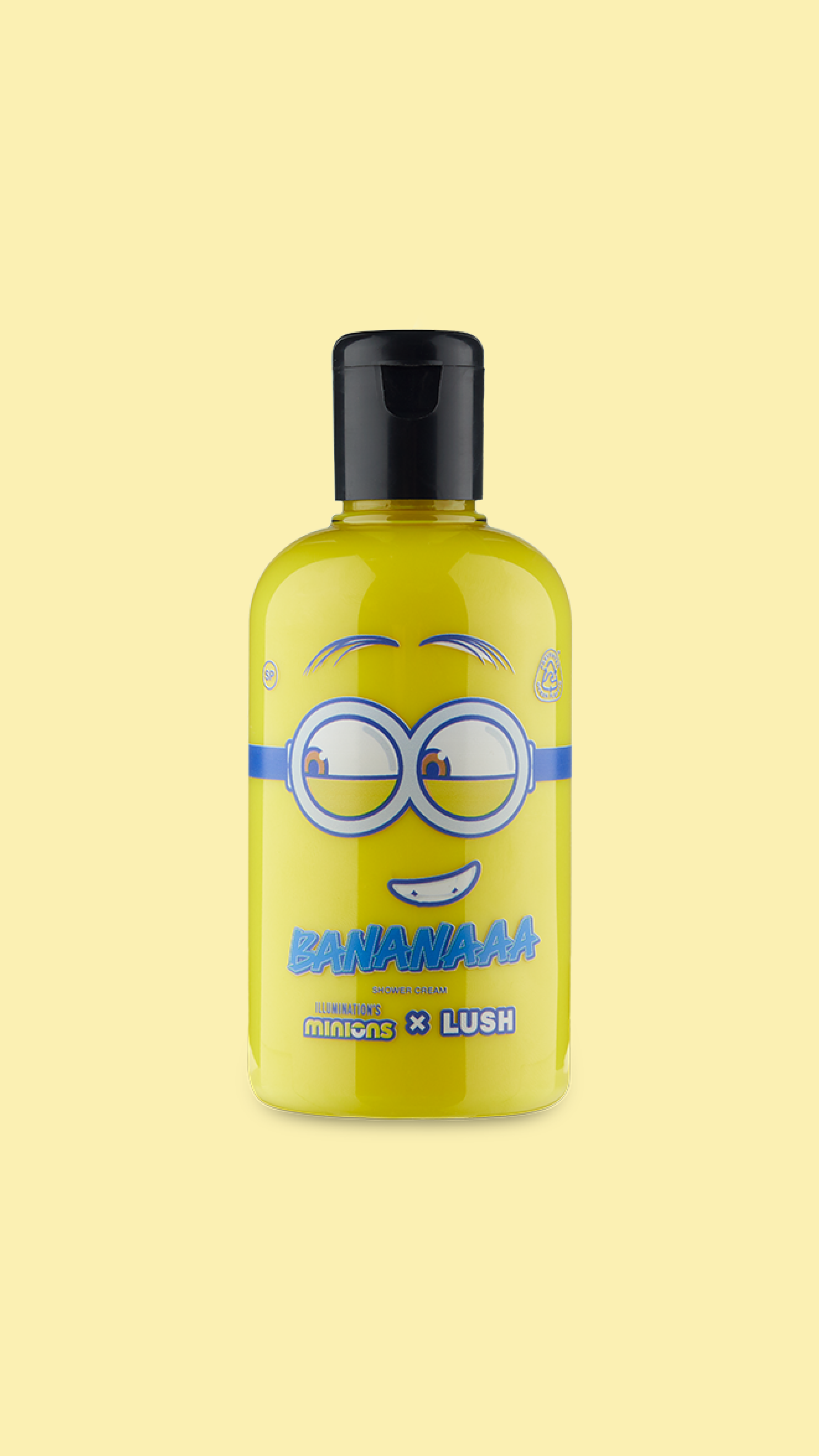 A classic LUSH shower gel bottle made with clear plastic. The bright yellow shower cream is visible through the bottle and there is a mischievous Minion face printed on the front.