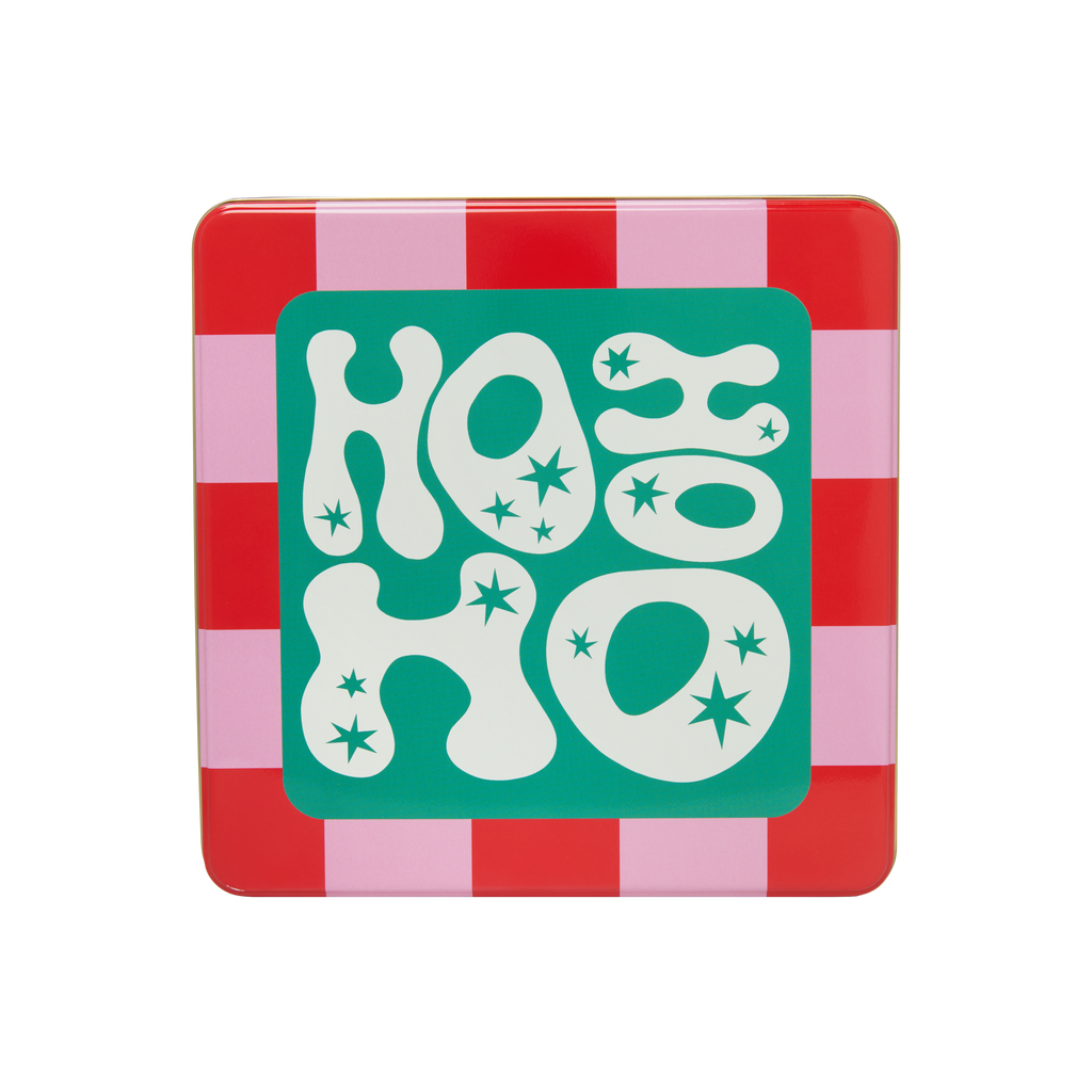 A close-up of a Lush "Ho Ho Ho" tin. The top of the tin is a red and pink checkerboard pattern with a bright teal square in the center that reads "HO HO HO" in white, bubbly letters with small stars.