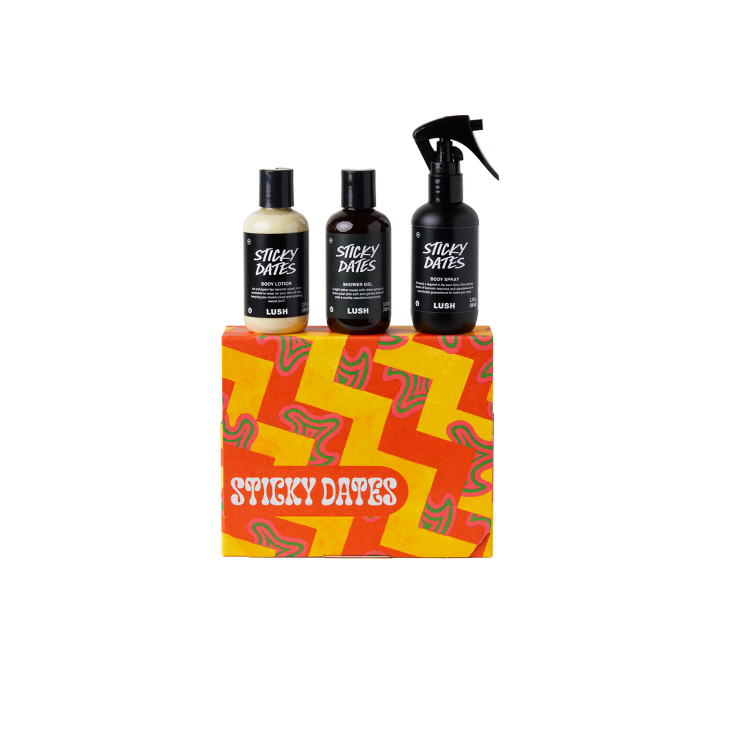 Sticky Dates. A square gift box wrapped in orange and yellow zigzag patterned paper. Three LUSH products are sitting on top of the box including Sticky Dates body lotion, shower gel and body spray.