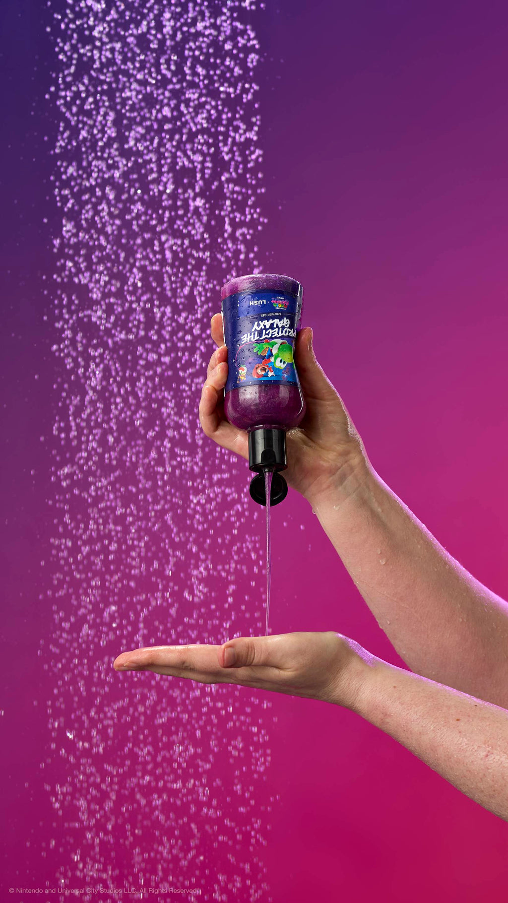One hand squeezes shimmering purple shower gel into another palm against a purple gradient and shower spray. The label features Mario on Yoshi. All glitter used is plastic-free.