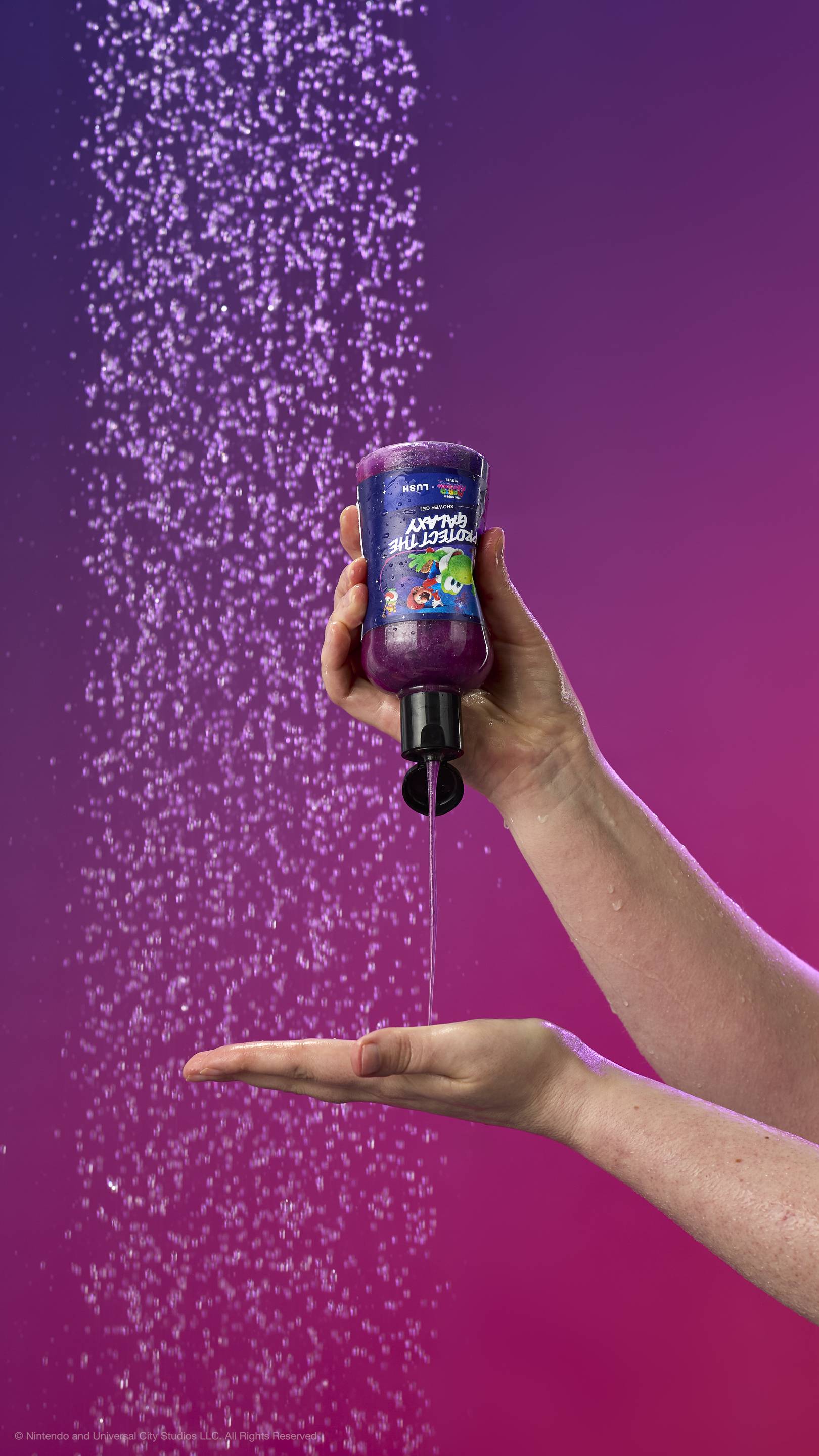 One hand squeezes shimmering purple shower gel into another palm against a purple gradient and shower spray. The label features Mario on Yoshi. All glitter used is plastic-free.