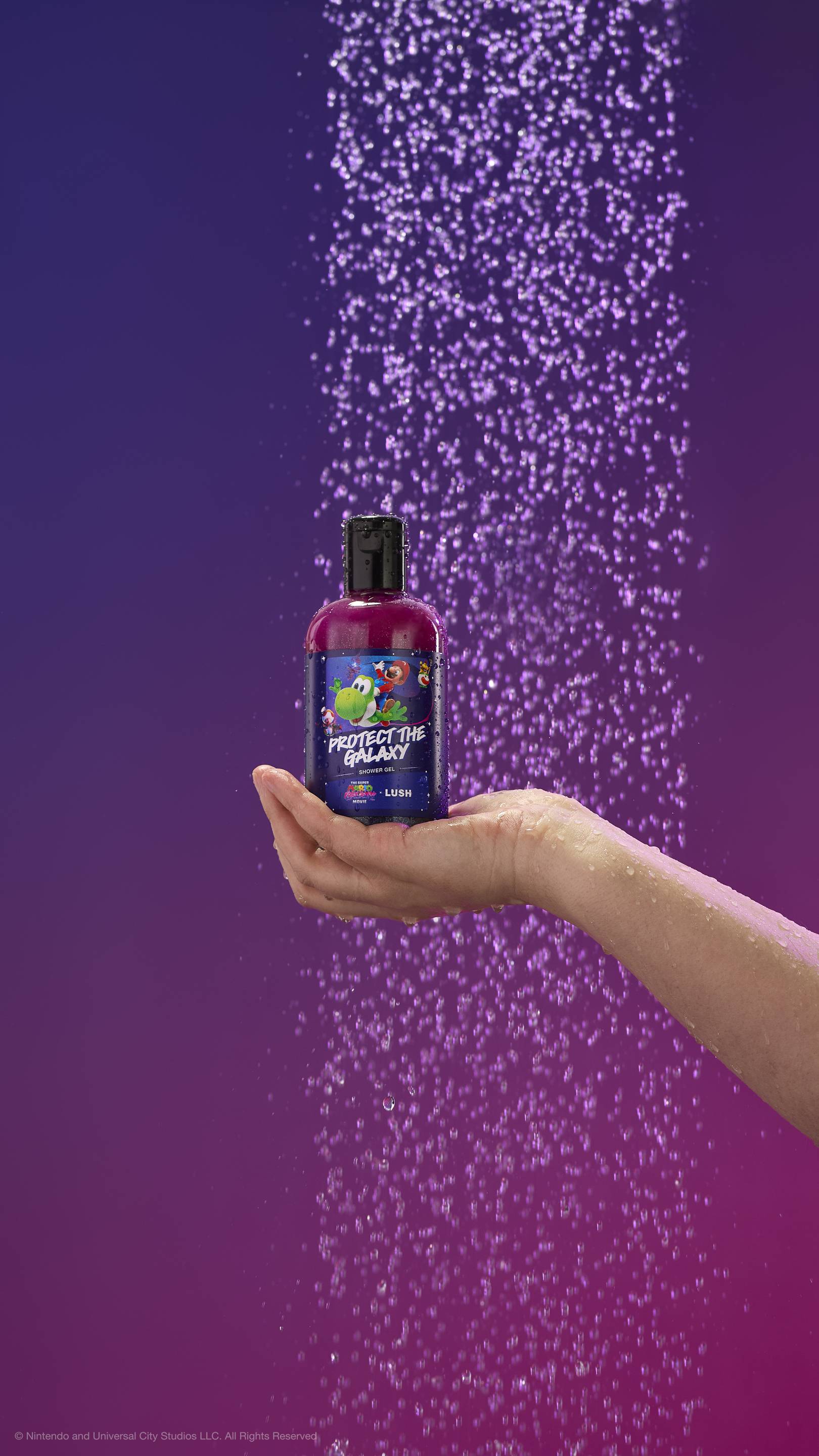 A hand holds a shimmering purple shower gel bottle under a spray of purple-tinted water. The label features Mario riding Yoshi. Against a purple gradient background. All glitter used is plastic-free.