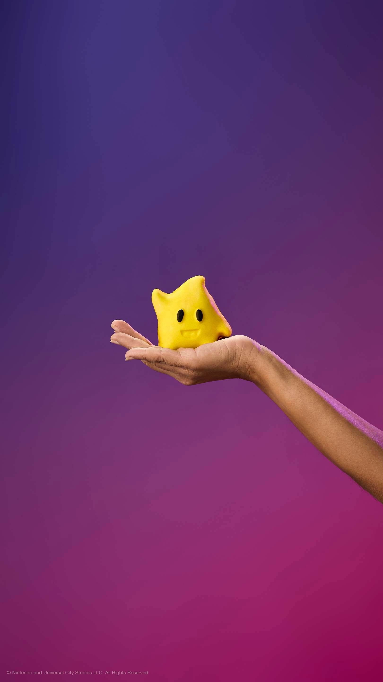 A hand holds a yellow star-shaped character bubble bar with a curl on top, black eyes, and a smile against a purple gradient background.