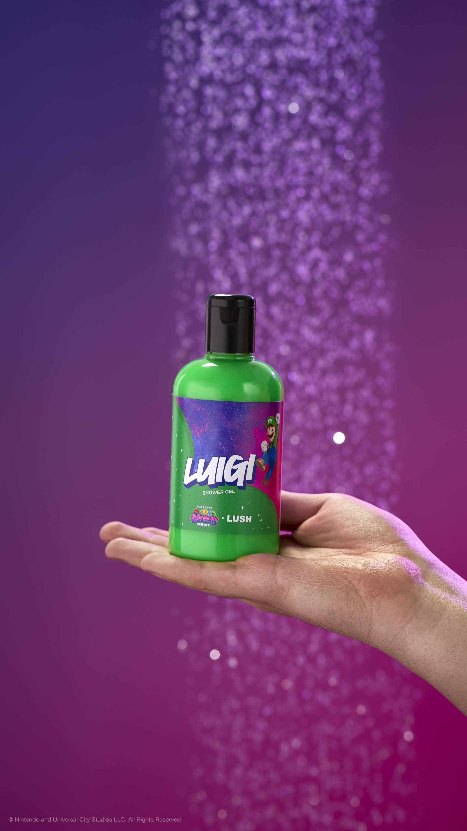 Hand holds a green Luigi shower gel bottle against a purple background with blurred water. Label features Luigi in space with movie and LUSH logos.