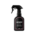 Sakura body spray. A black spray bottle of Lush "Sakura" Body Spray. The product label is black with a pastel-pink banded border. White text states the product name and the scent description.