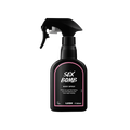 Sex Bomb body spray. A black spray bottle of Lush "Sex Bomb" Body Spray. The product label is black with a dusky pink banded border. White text states the product name and the scent description.