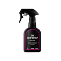 The Comforter body spray. A black spray bottle of Lush "The Comforter" Body Spray. The product label is black with a hot pink banded border. White text states the product name and the scent description.