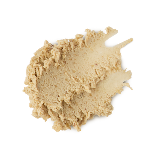 The image shows a neatly smudged swatch of thick, textured, ivory/sand-coloured, paste-like face cleanser product.