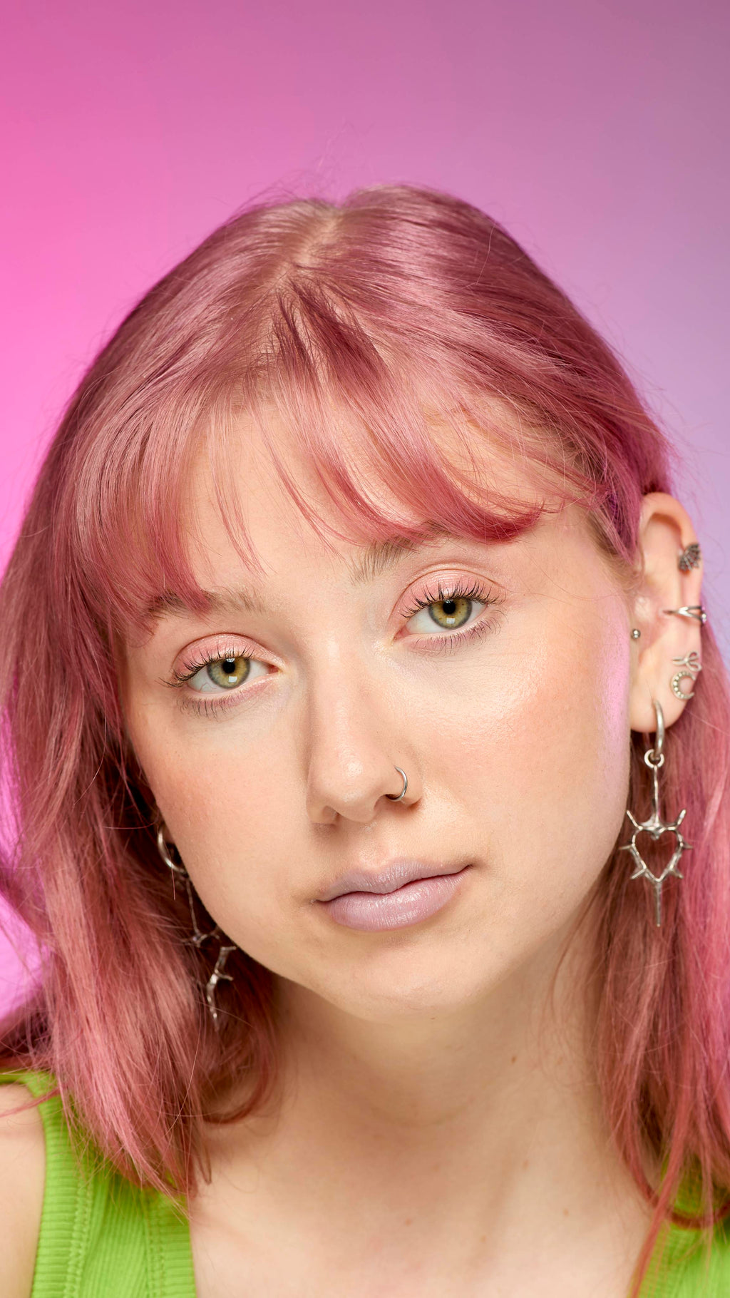 The image shows a fair-skinned model on a pink and blue gradient background. They have pink hair and subtle, blue shimmering lips from using the Blue Pearl lip cream.