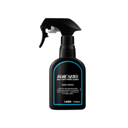 A recycled black plastic LUSH body spray bottle with a trigger nozzle stands upright with a blue rimmed label with white text that reads "Blue Skies and Fluffy White Clouds Body Spray".