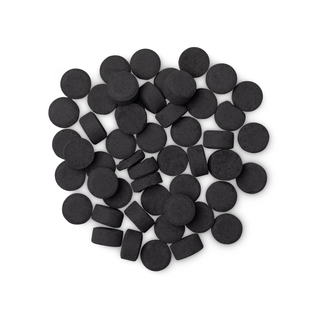 A pile of small, circular, black Boom! toothpaste tabs shot from above.
