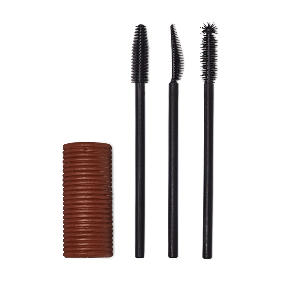 A Solid cylindrical block of brown mascara next to three different style mascara spoolie brushes.