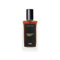 A glass perfume bottle filled with mahogany liquid. A black label reads 'The Perfume Library' and 'Cardamom Coffee'.