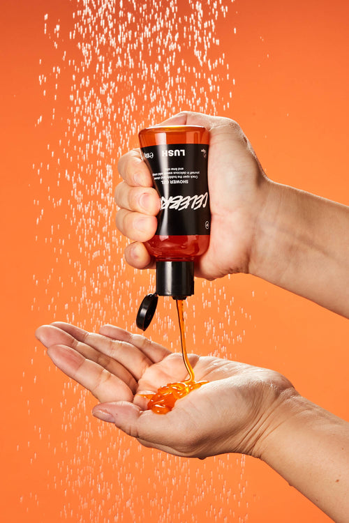 A close-up of the model's hand as they squeeze the Celebrate shower gel into their hand under running shower water.