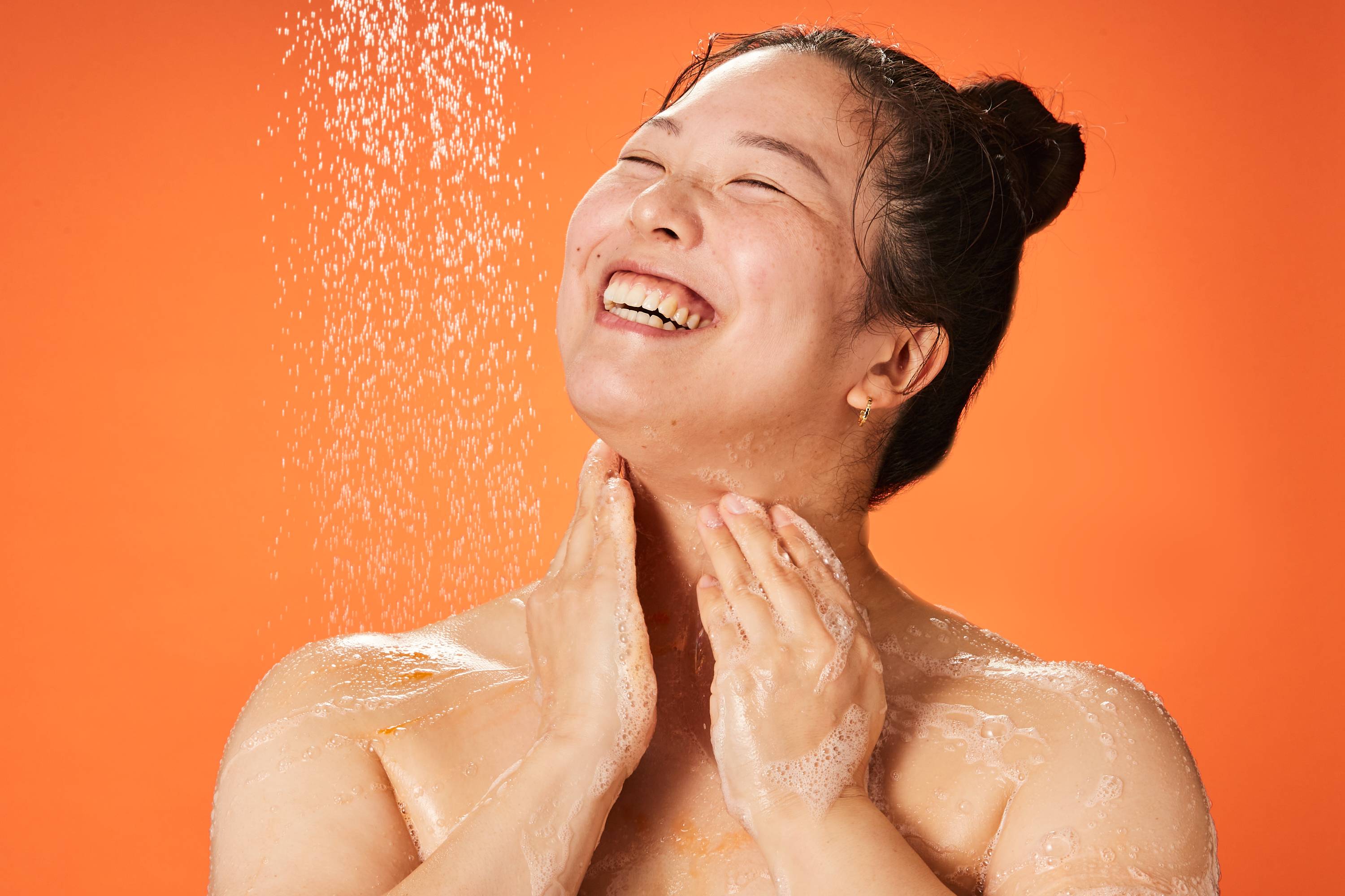 We see from shoulders and above as the model is under the shower water lathering up their skin with Celebrate shower gel.