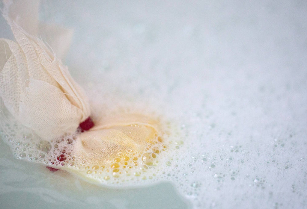 The muslin cloth and red ribbon of Ceridwen's Cauldron sticks out of the water topped with white bubbles.