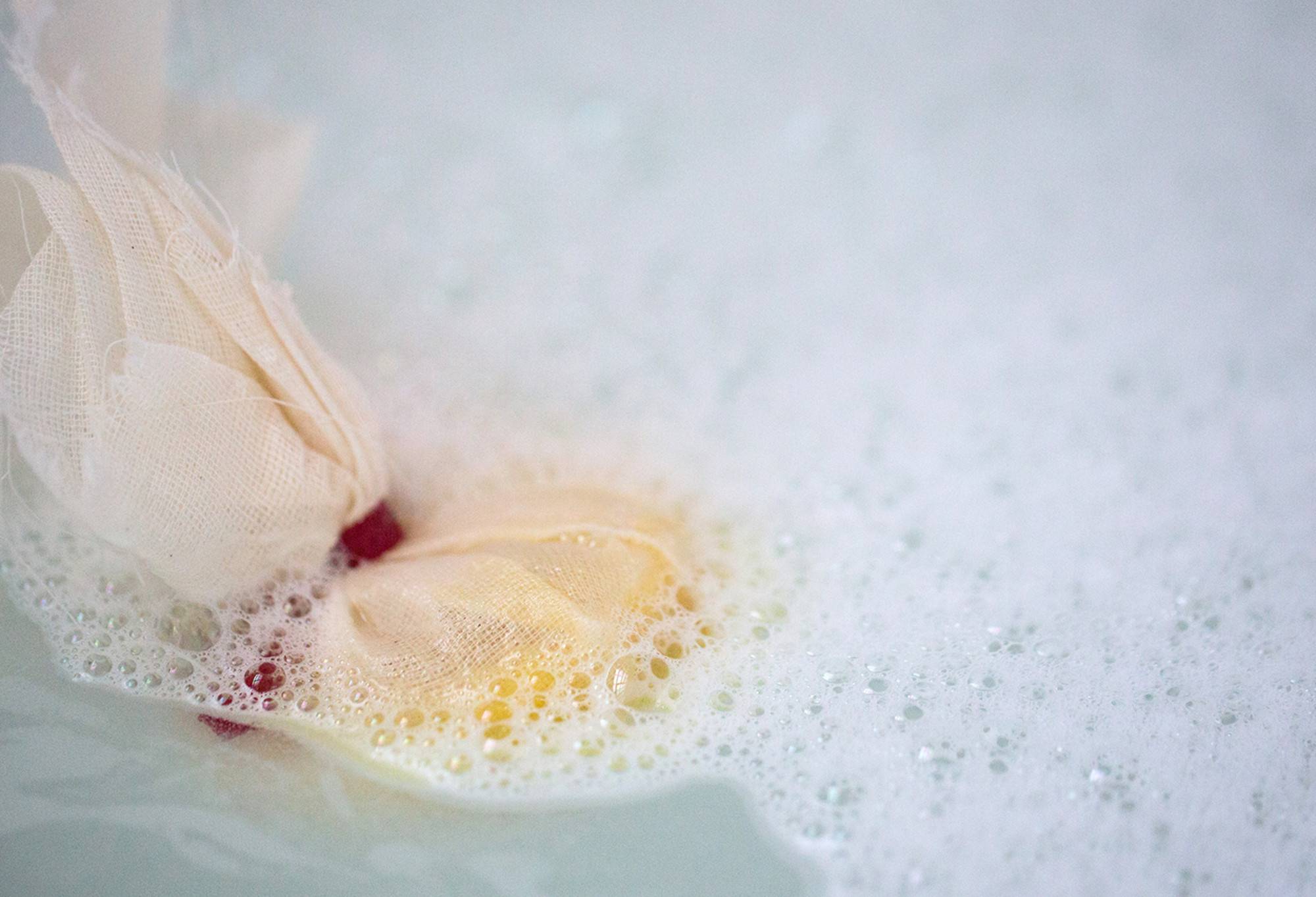 The muslin cloth and red ribbon of Ceridwen's Cauldron sticks out of the water topped with white bubbles.