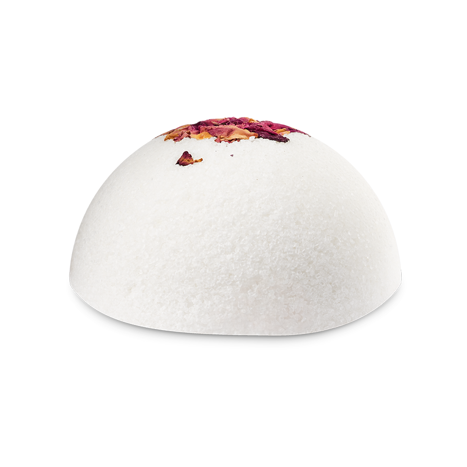 The Rose Comforter. A white, dome-shaped solid body scrub with a crystalline, salt-like texture. The top of the sphere is decorated with dried pink and yellow rose petals.
