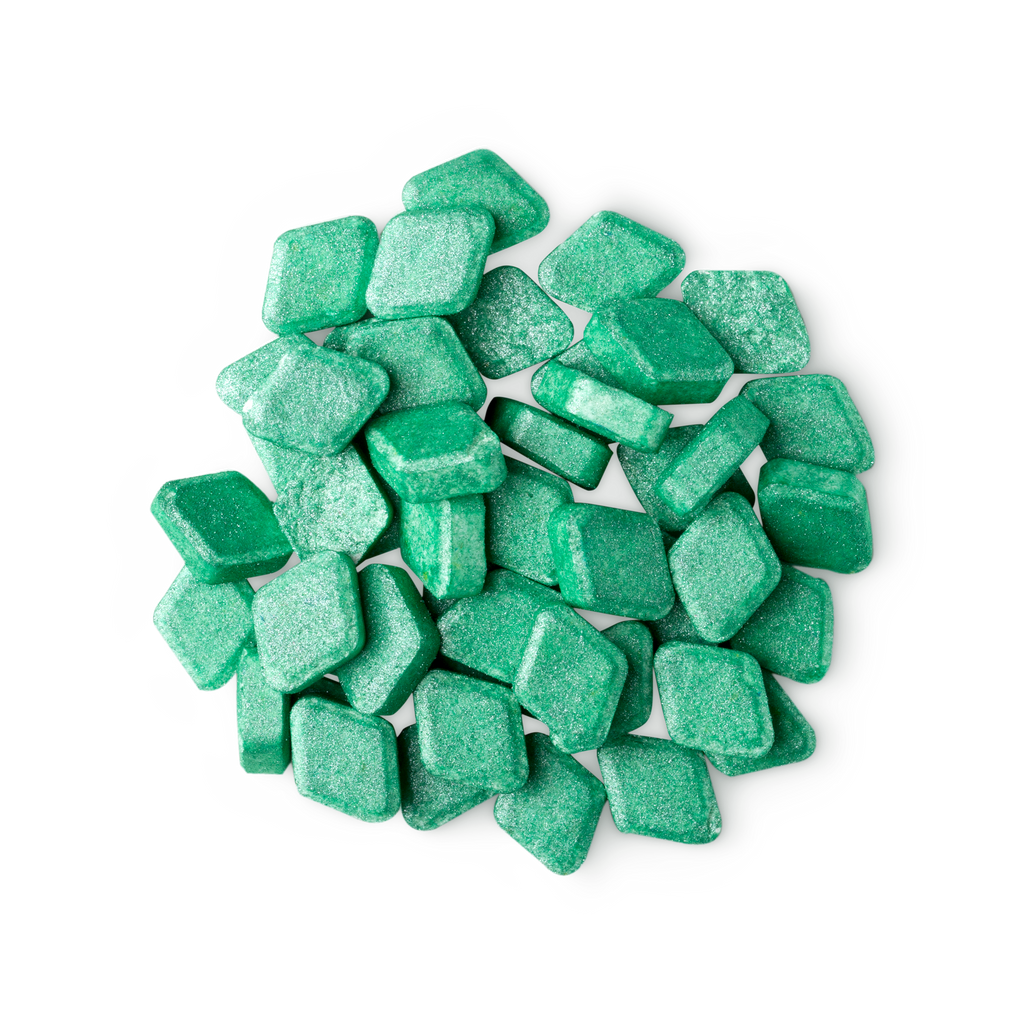 A pile of small, diamond-shaped, green Crème De Menthe mouthwash tabs shot from above.