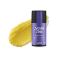 Dream Time. A smudged swatch of thick, natural yellow balm. In front of it stands the cylindrical black packaged Temple Balm with a purple product sticker.