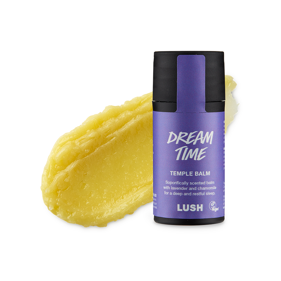 Dream Time. A smudged swatch of thick, natural yellow balm. In front of it stands the cylindrical black packaged Temple Balm with a purple product sticker.
