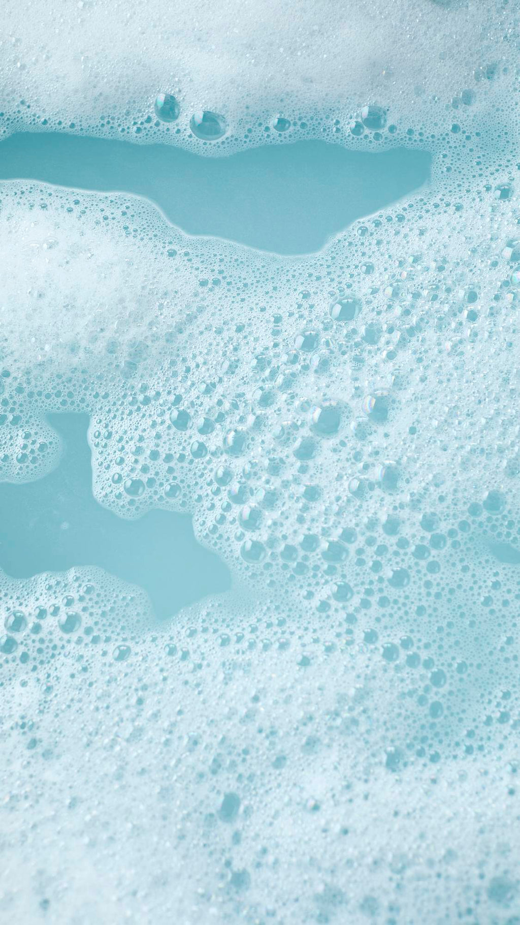 The image shows the colourful aftermath of using the Frozen reusable bubble bark stick. There is turquoise, icy-blue bath water surrounded by mountains of bright bubbles.