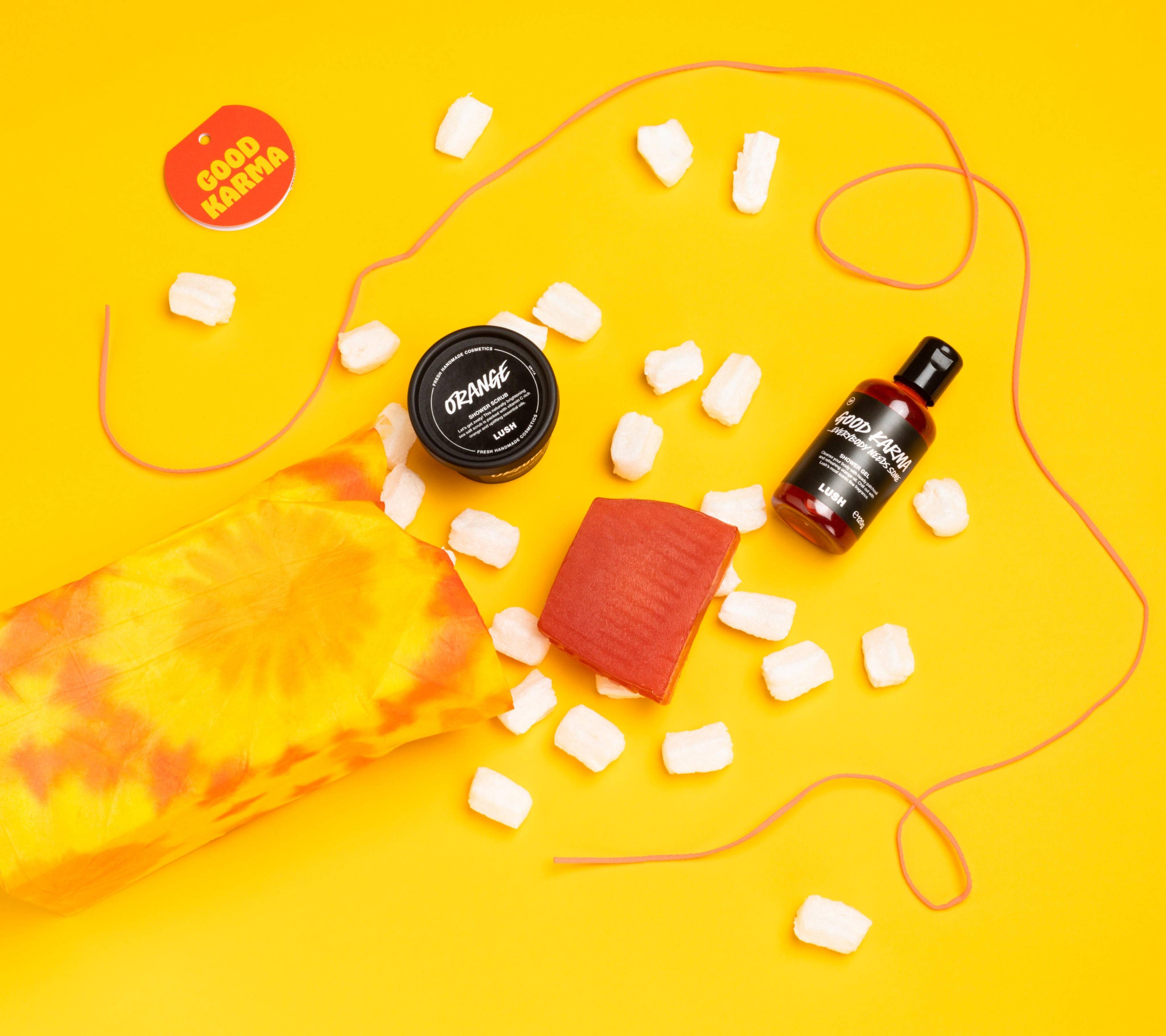 Good Karma, opened onto a bright yellow background, with its included products and eco packaging pops arranged randomly.