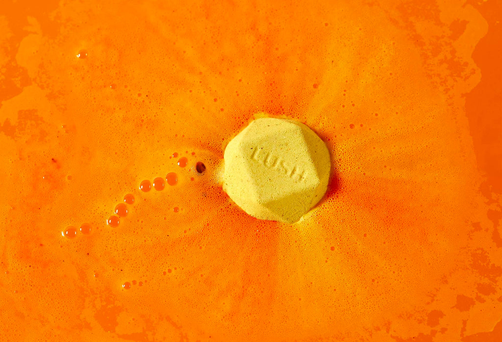 Hinata bath bomb. Bright yellow bath bomb sits among electric orange, silky foam.