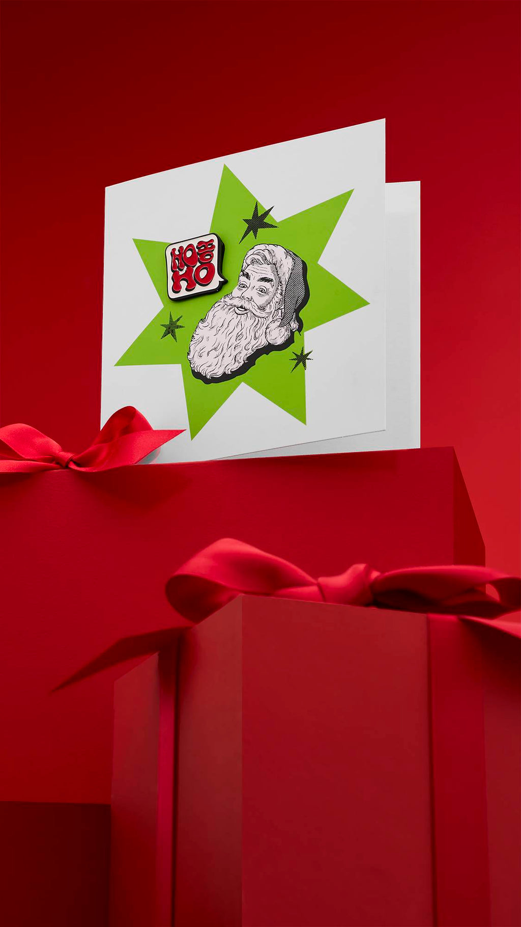 A festive "HO HO HO" greeting card with a comic-style design, featuring a classic black and white illustration of Santa Claus with a green starburst behind him. The card is displayed on a red background with wrapped gifts.