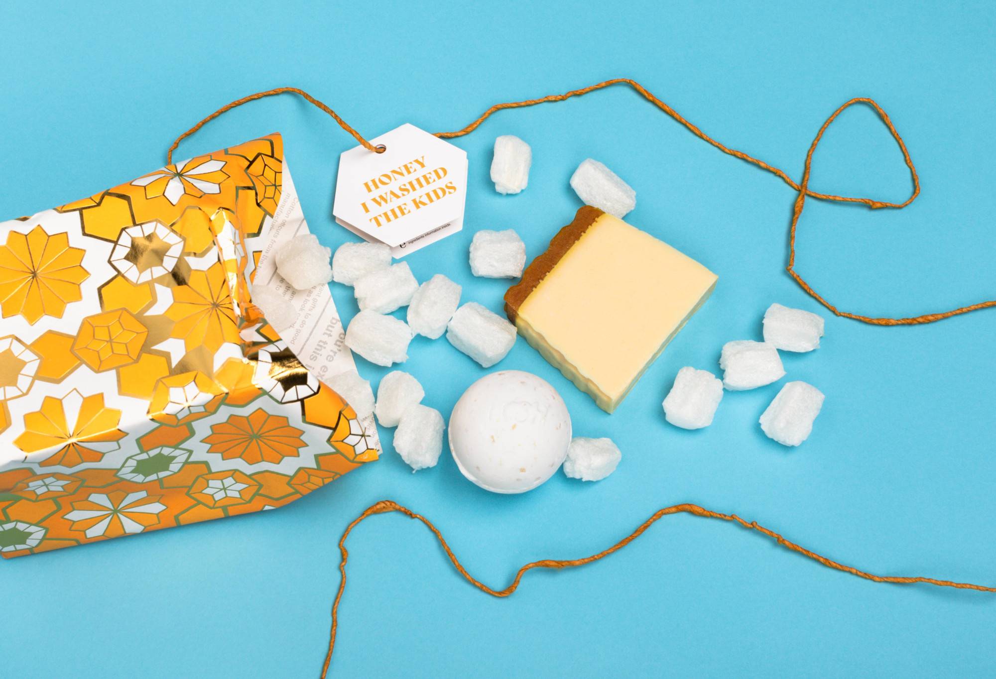 Honey I Washed the Kids, opened onto a blue background, with its included products and eco packaging pops arranged randomly.
