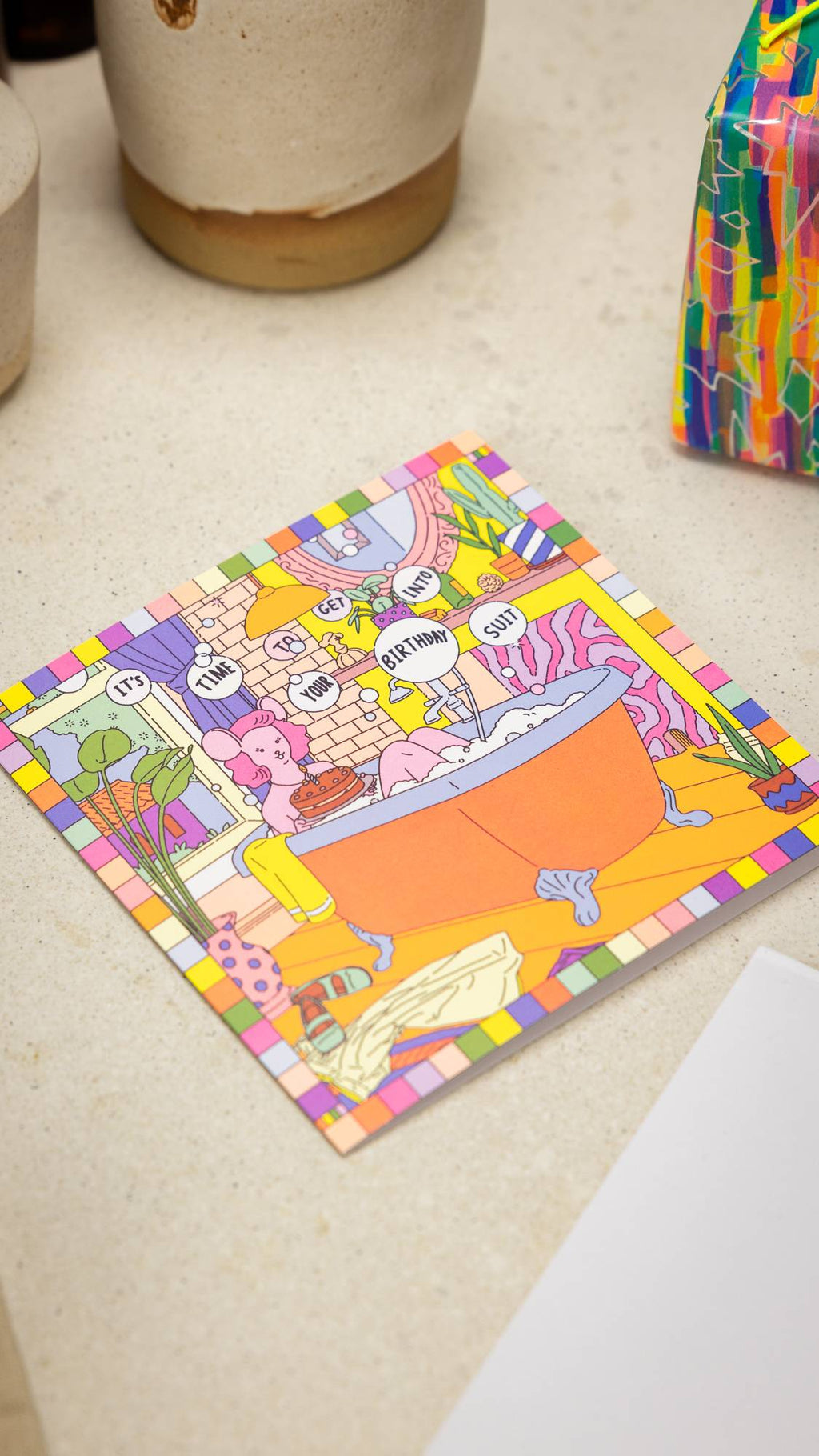 Image shows the "It's Time To Get Into Your Birthday Suit" laid flat on a table with a wrapped gift beside.