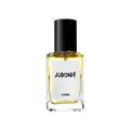 A rectangular glass bottle of Lush 'Karma' perfume with a black cap, filled with light yellow liquid, stands against a solid black background. The white textured label features the name "KARMA" in stylised black lettering.