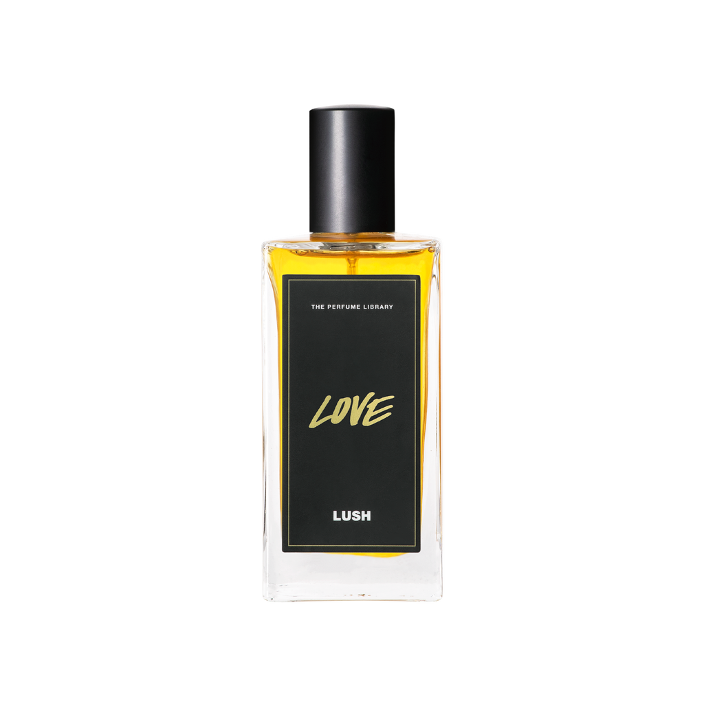 A glass perfume bottle filled with light amber liquid. A black label reads 'The Perfume Library' and 'Love'.
