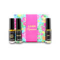 The image shows a "LUSH Romance" perfume gift set. Three thin glass perfume bottles with amber and clear liquids are arranged around a light blue box with vibrant floral patterns and a bright pink band.