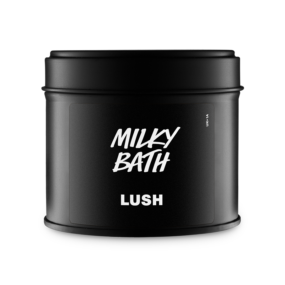 A matte black circular tin with a matching lid. The front label features the Lush logo and the product name "Milky Bath" in bold, white hand-drawn style typography. Set against a plain grey background.