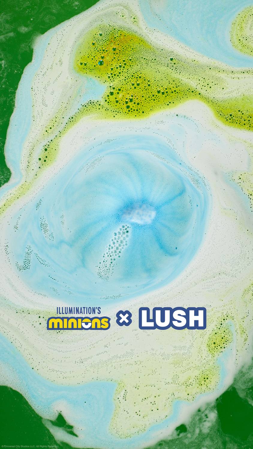 The Minions bath bomb has fully dissolved leaving behind ribbons of blue and green swirling foam. The Minions X LUSH logo is at the bottom.