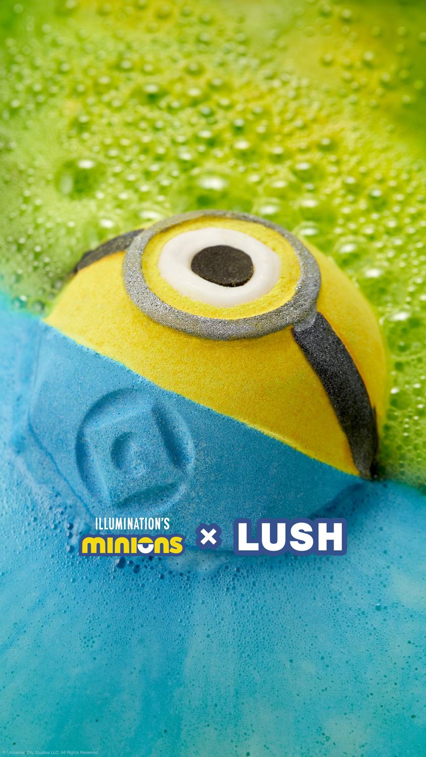 The Minions bath bomb is gently being paced into the bath water as it starts to give off deep blue foam from the lower half and neon green foam from the top half.