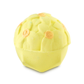 A pale yellow, dome-shaped bath bomb with a detailed floral pattern on top. Several of the molded flower centers are accented with a shimmering gold finish.