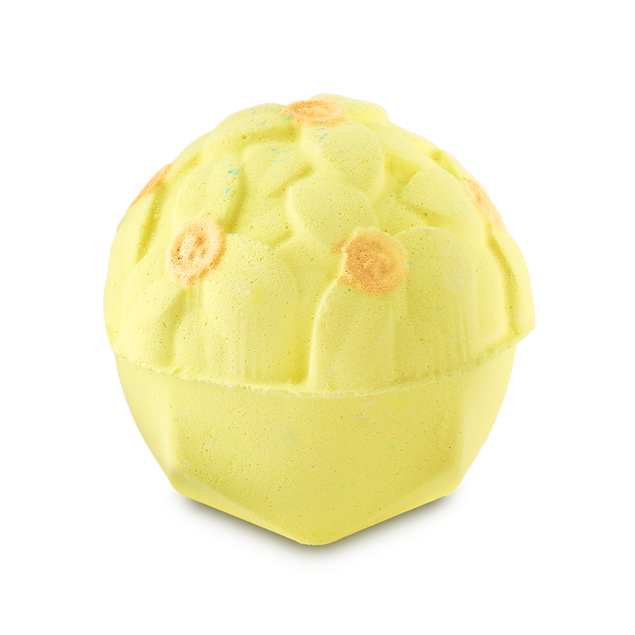 A pale yellow, dome-shaped bath bomb with a detailed floral pattern on top. Several of the molded flower centers are accented with a shimmering gold finish.