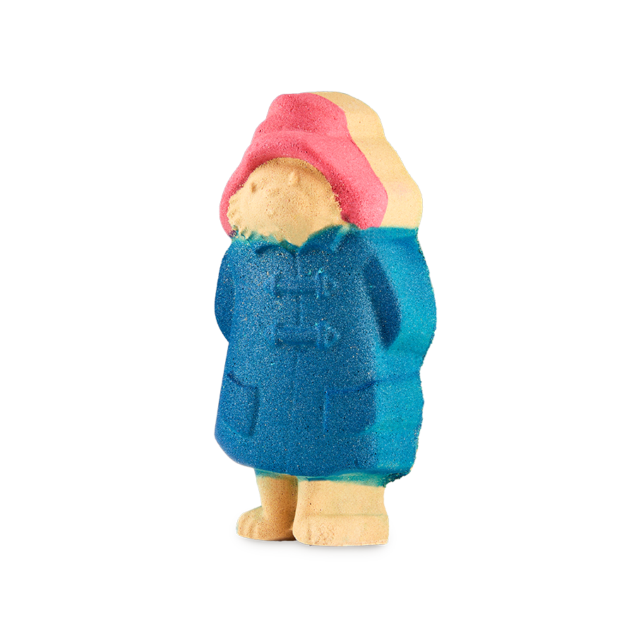 Paddington. A detailed bath bomb shaped like Paddington Bear, wearing his iconic red hat and blue raincoat. The character is standing upright and features a slight glitter in the blue coat.