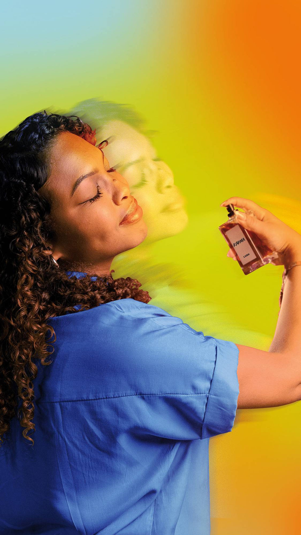 A person with curly hair in a blue shirt sprays Lush 'Karma' perfume, eyes closed in bliss. A motion-blurred trail follows them against a vibrant teal, yellow, and orange gradient background, capturing a sensory, uplifting mood.
