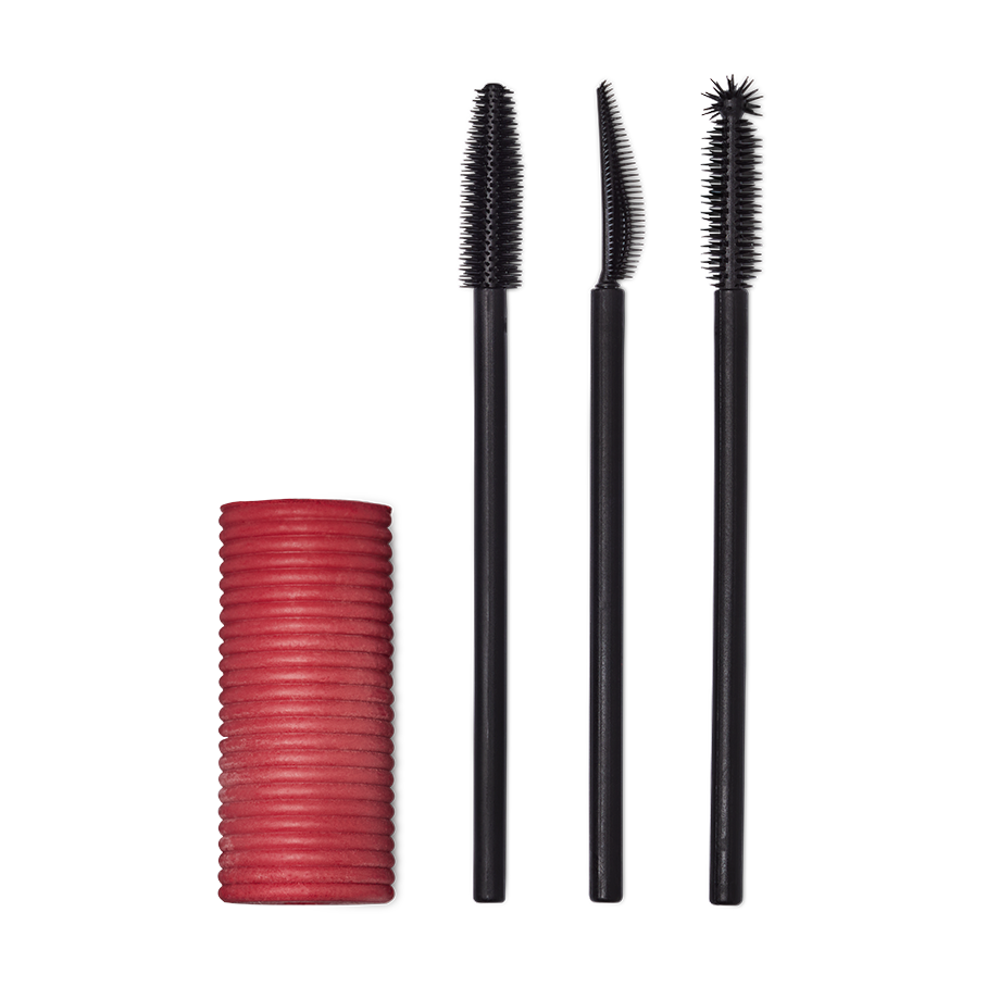 A Solid cylindrical block of pink mascara next to three different style mascara spoolie brushes.